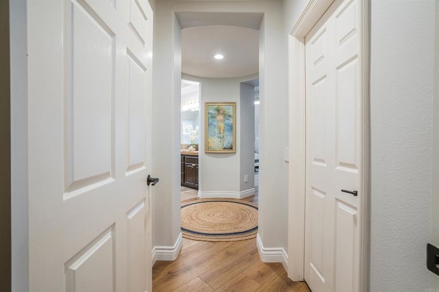 corridor with light wood-style floors, baseboards, and recessed lighting