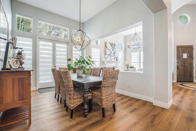 dining area featuring an inviting chandelier, baseboards, and light wood-style flooring