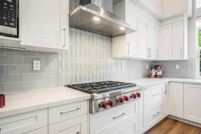 kitchen with wall chimney range hood, white cabinetry, appliances with stainless steel finishes, and tasteful backsplash