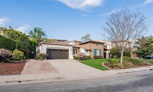 mediterranean / spanish home featuring an attached garage, a front lawn, a tile roof, stucco siding, and concrete driveway