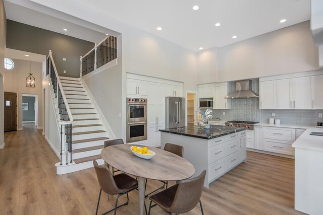 2463 Springbrook St, Thousand Oaks, CA 91362 - kitchen with wall chimney exhaust hood, a high ceiling, appliances with stainless steel finishes, a kitchen island, and tasteful backsplash