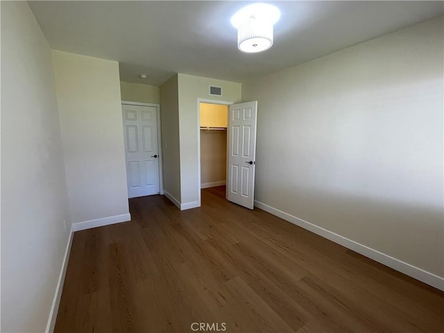 unfurnished bedroom with visible vents, baseboards, a closet, and wood finished floors