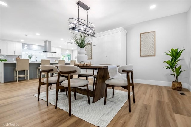 dining room with baseboards, light wood-type flooring, an inviting chandelier, and recessed lighting