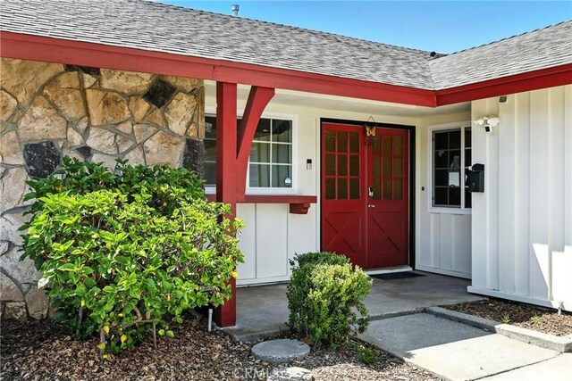 2842 Pietro Dr, Hacienda Heights, CA 91745 - doorway to property featuring a shingled roof, stone siding, covered porch, and board and batten siding