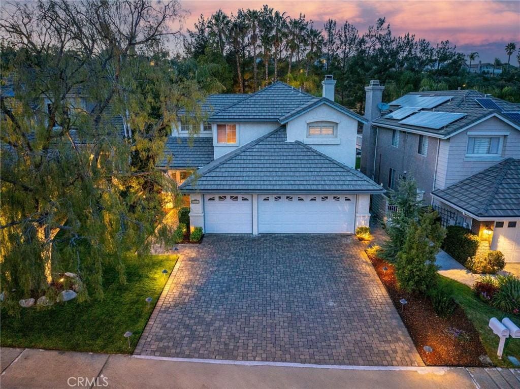 25641 Shaw Pl, Stevenson Ranch, CA 91381 - traditional-style house with a tiled roof, an attached garage, a chimney, stucco siding, and decorative driveway