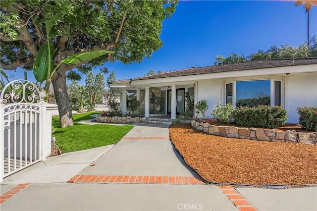 view of front of home featuring stucco siding, a gate, and a front lawn