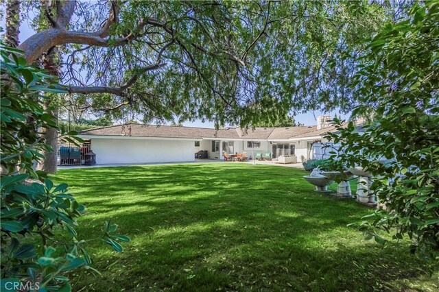 view of front facade with a front lawn, a patio, and stucco siding