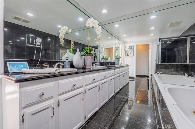 bathroom with a whirlpool tub, double vanity, recessed lighting, granite finish floor, and visible vents