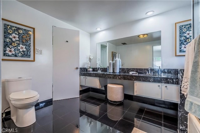 bathroom with tile patterned flooring, double vanity, a sink, and toilet