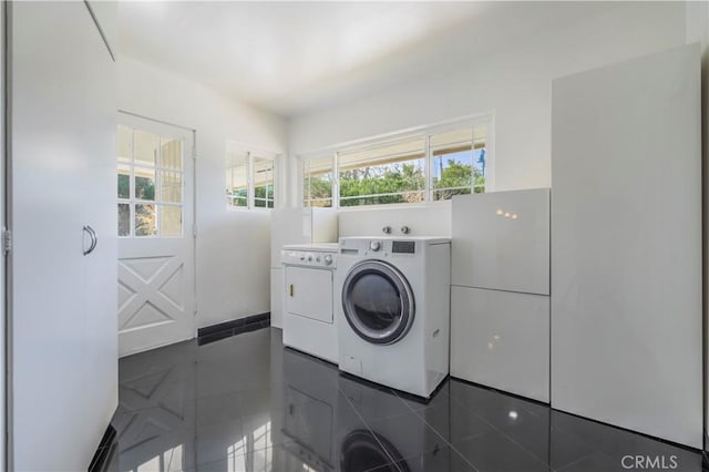 clothes washing area featuring dark tile patterned flooring, laundry area, and washer and clothes dryer