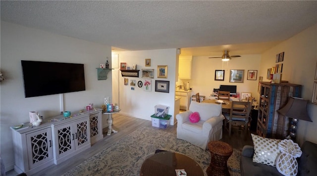 2189 Via Mariposa # C, Laguna Woods, CA 92637 - living area with a desk, wood finished floors, ceiling fan, a textured ceiling, and baseboards