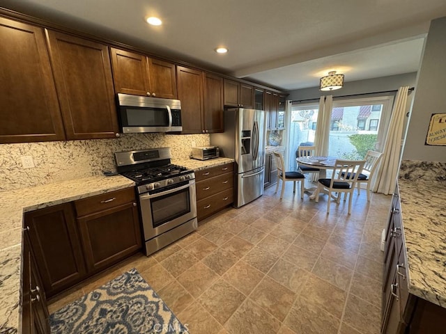 2244 Cannes Sq, Oxnard, CA 93035 - kitchen featuring appliances with stainless steel finishes, decorative backsplash, dark brown cabinets, light stone counters, and recessed lighting