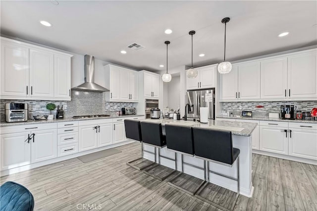 8794 Applewood St, Chino, CA 91708 - kitchen featuring visible vents, wall chimney exhaust hood, a breakfast bar, white cabinetry, and stainless steel appliances