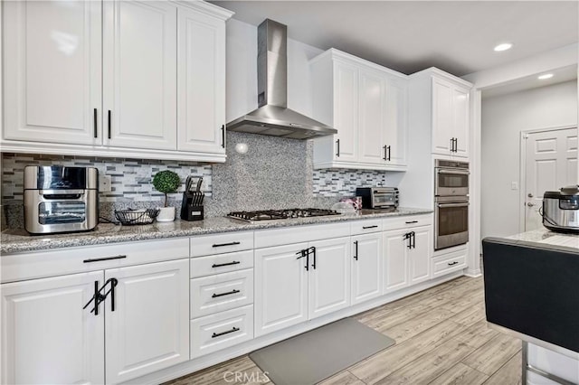 8794 Applewood St, Chino, CA 91708 - kitchen featuring wall chimney exhaust hood, white cabinetry, appliances with stainless steel finishes, light wood finished floors, and decorative backsplash