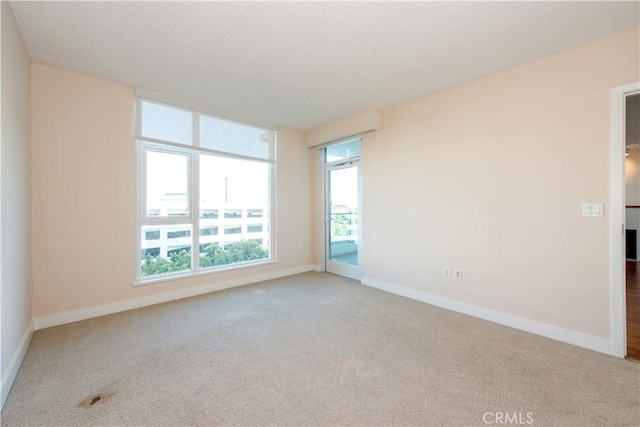 spare room with baseboards and carpet floors