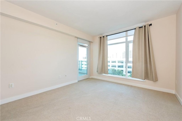 unfurnished room with light colored carpet and baseboards