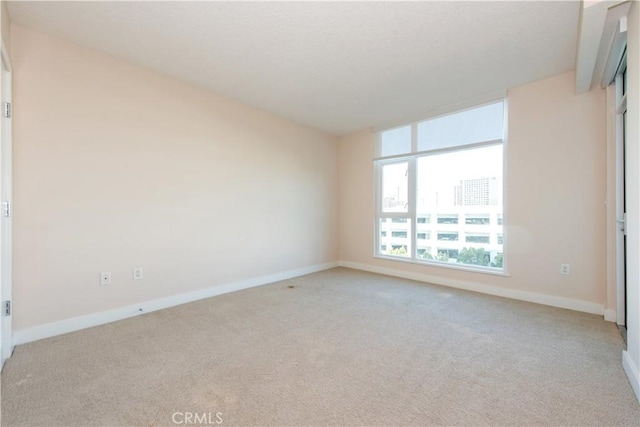empty room featuring light carpet and baseboards