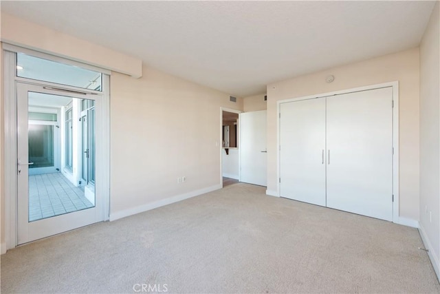 unfurnished bedroom with baseboards, visible vents, a closet, and light colored carpet