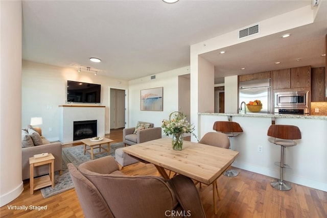 dining room with visible vents, a fireplace, light wood-style flooring, and recessed lighting