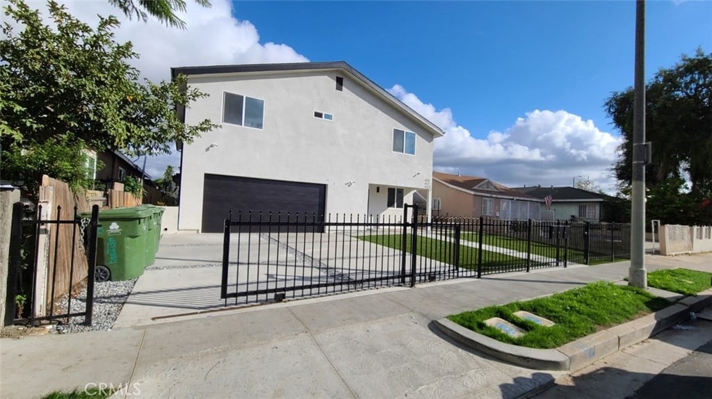 view of front of home with a fenced front yard, an attached garage, concrete driveway, and stucco siding