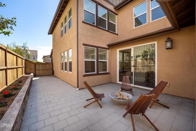 rear view of property with a fire pit, a patio, stucco siding, and fence