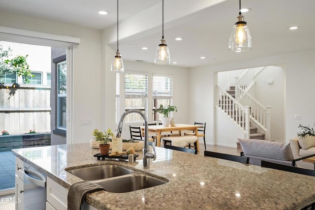 kitchen with stainless steel dishwasher, pendant lighting, white cabinetry, and a sink