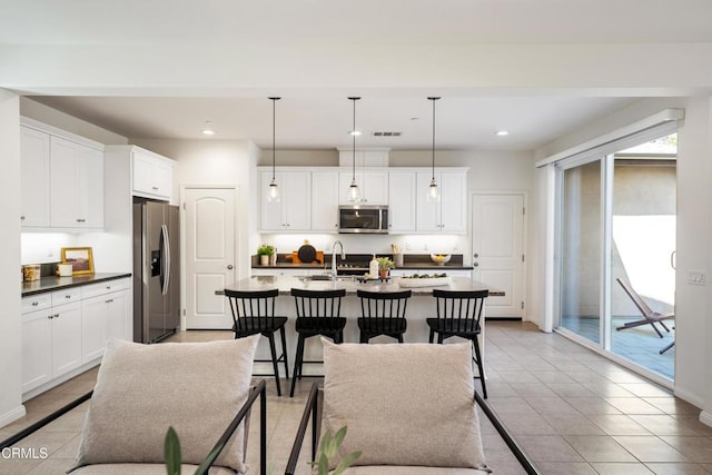 kitchen with white cabinetry, visible vents, a breakfast bar, appliances with stainless steel finishes, and light tile patterned flooring