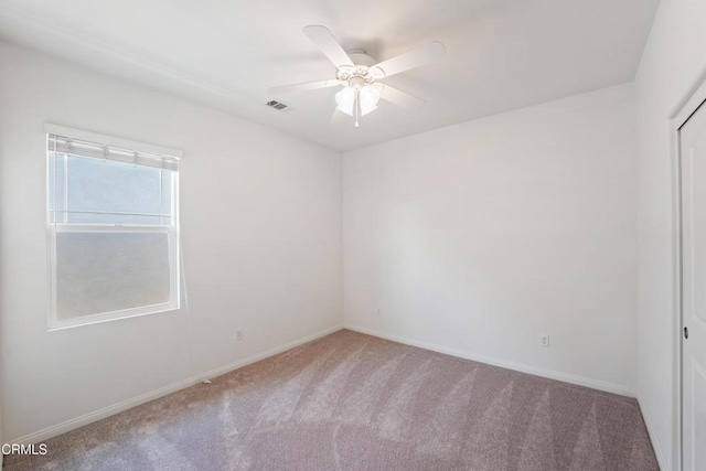 spare room with carpet flooring, baseboards, a ceiling fan, and visible vents