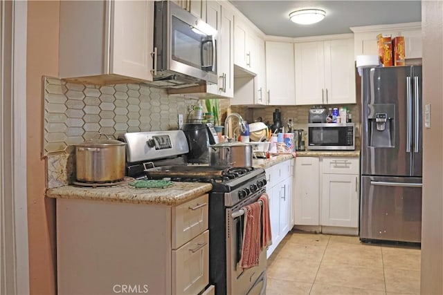 kitchen with white cabinetry, light tile patterned flooring, backsplash, and appliances with stainless steel finishes