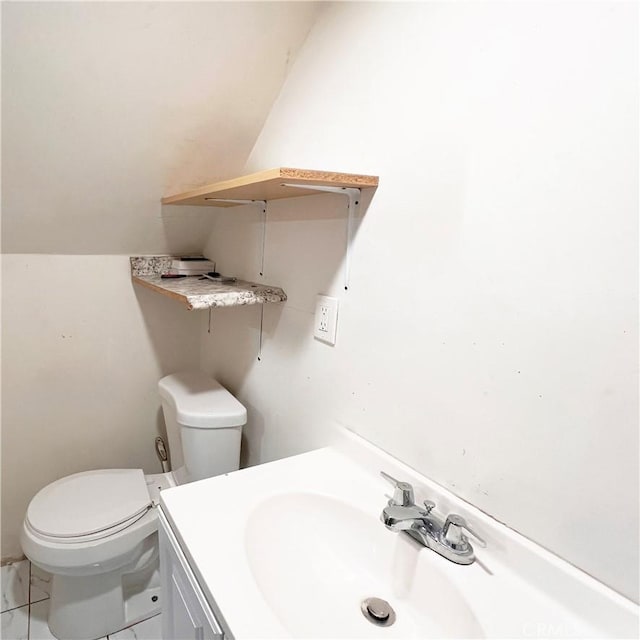 bathroom with toilet, vanity, and vaulted ceiling