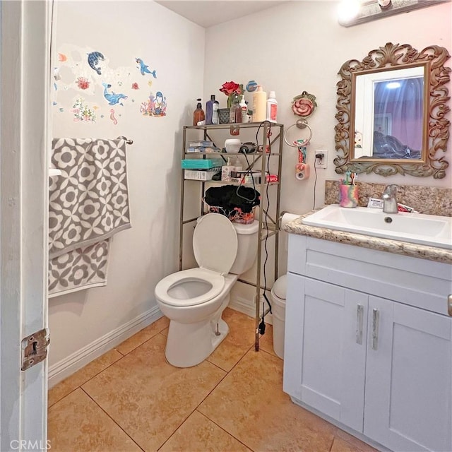 bathroom featuring tile patterned flooring, vanity, baseboards, and toilet