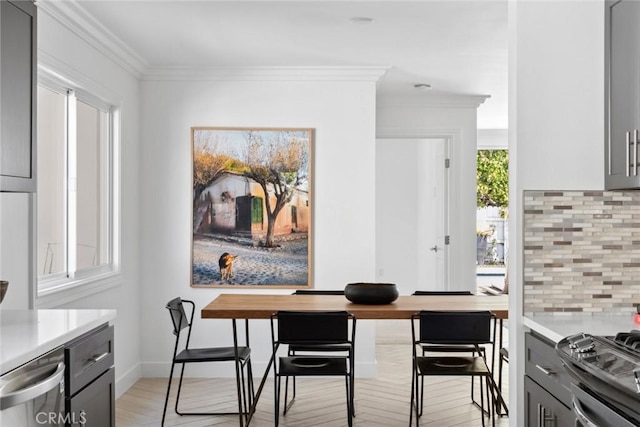 dining space with ornamental molding and light wood-style floors