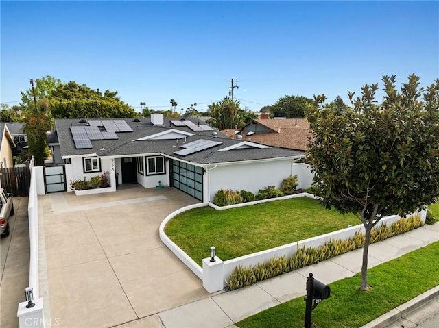 view of front facade featuring driveway, roof mounted solar panels, roof with shingles, an attached garage, and fence