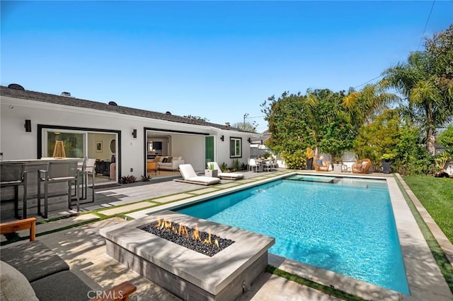 pool with a fire pit and a patio area