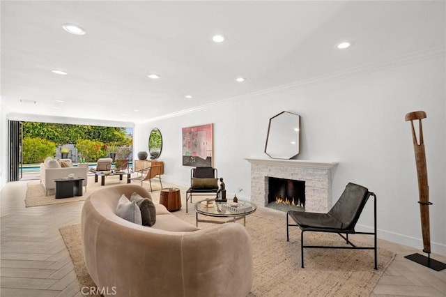living area with baseboards, recessed lighting, a stone fireplace, and crown molding