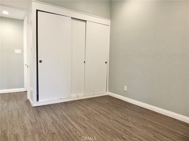 unfurnished bedroom featuring recessed lighting, dark wood finished floors, a closet, and baseboards