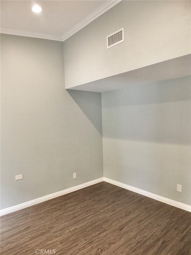 spare room with baseboards, ornamental molding, dark wood-type flooring, and visible vents