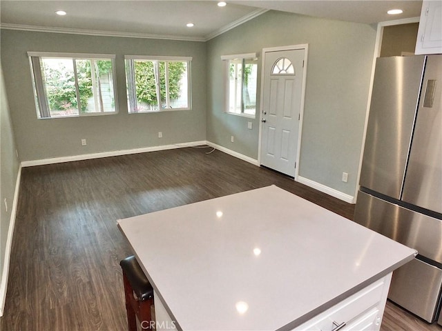 kitchen with dark wood finished floors, freestanding refrigerator, crown molding, and white cabinetry
