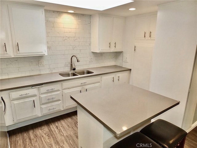kitchen featuring dark wood finished floors, white cabinetry, tasteful backsplash, and a sink