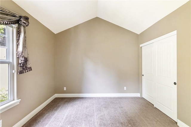 interior space with baseboards, carpet, and vaulted ceiling