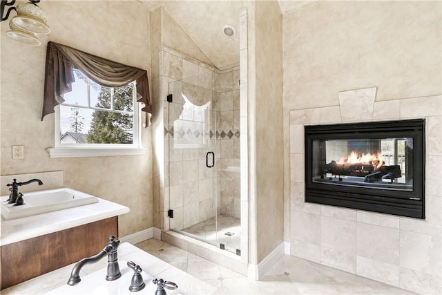 full bathroom with a multi sided fireplace, a shower stall, a sink, tile patterned floors, and baseboards