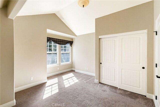 unfurnished bedroom featuring carpet, a closet, baseboards, and lofted ceiling