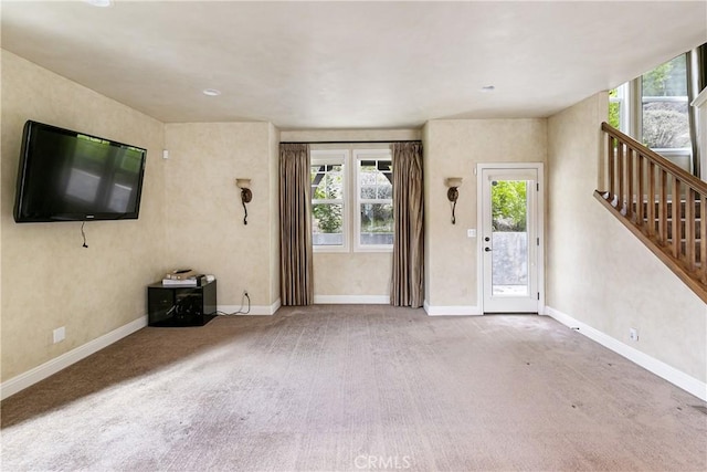 unfurnished living room with stairs, carpet, and baseboards