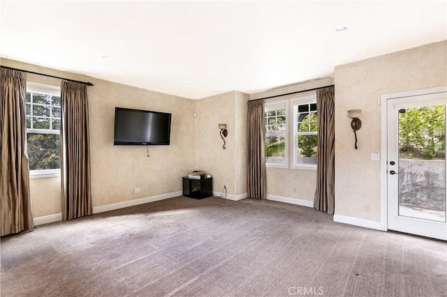 unfurnished living room featuring plenty of natural light, baseboards, and carpet floors