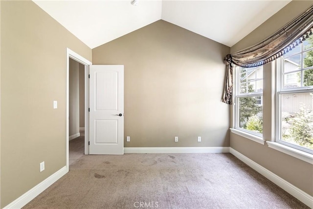 unfurnished room featuring baseboards, lofted ceiling, and a wealth of natural light