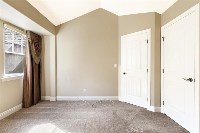 carpeted empty room with baseboards and lofted ceiling