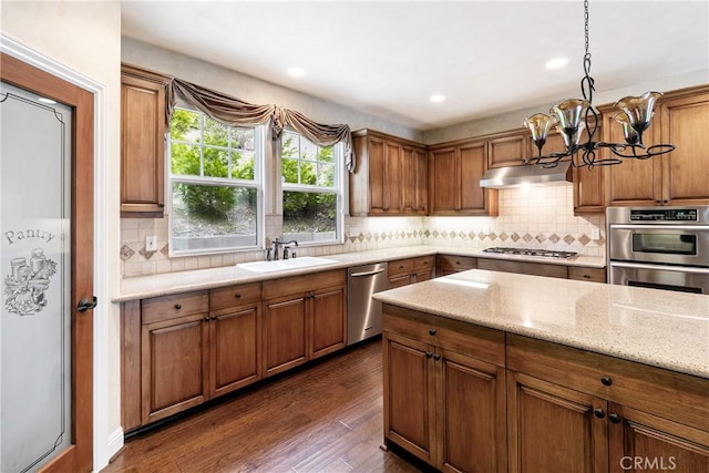 kitchen with a notable chandelier, brown cabinets, a sink, and appliances with stainless steel finishes