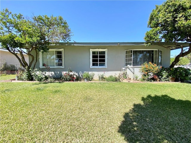 ranch-style home with a front lawn, stucco siding, and fence