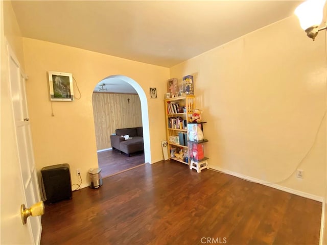 unfurnished room with arched walkways and wood finished floors