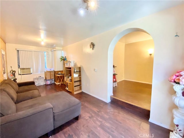 living room with arched walkways, baseboards, cooling unit, and wood finished floors